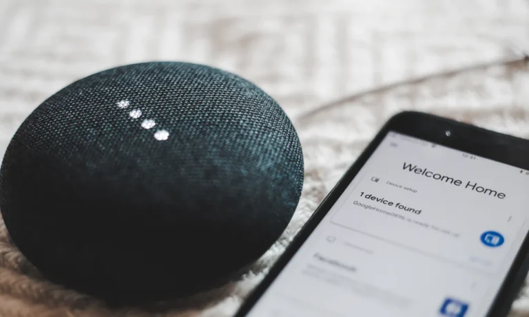 Closeup of a Google home speaker and the home page of the app that manages it